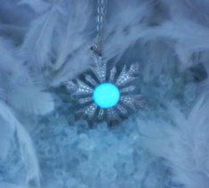 a snowflake ornament in the middle of feathers with a blue light shining on it