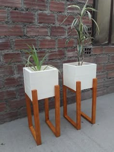 two white planters sitting next to each other near a brick wall