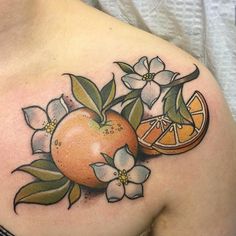 an orange and flower tattoo on the shoulder