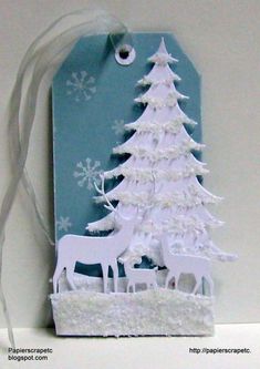 a white christmas tree with deer and snowflakes on it is next to a tag