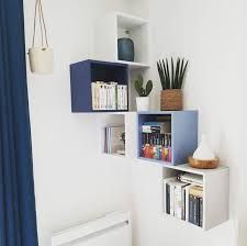 a shelf with books and plants on it in the corner of a room next to a radiator