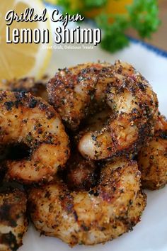 grilled cajun lemon shrimp is served on a white plate next to a lemon wedge