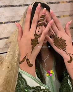 a woman with her hands on her face covered in hendi tattoos, covering her eyes