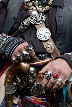 a close up of a person with many rings on their hands and bracelets around his neck