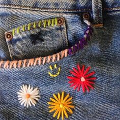 the back pocket of a pair of jeans with colorful embroidered flowers on them and words written in small letters