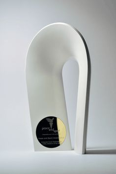 a white sculpture sitting on top of a table next to a black and yellow plaque