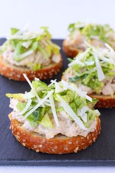 small sandwiches with lettuce and cheese on top are sitting on a black plate