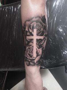 a cross and roses tattoo on the arm