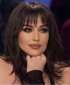 a close up of a woman with long hair and brown eyeshadow wearing black gloves