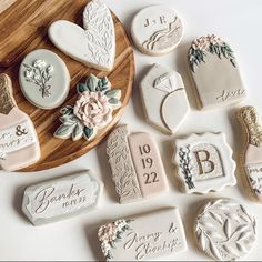 wedding cookies and cookie cutters on a wooden platter with the names of their guests