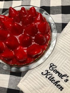 a dessert dish with strawberries in it on a checkered table cloth and napkin