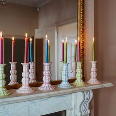 candles are lined up on a mantle in front of a mirror