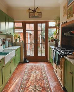 a kitchen with green cabinets and an area rug on the floor in front of it