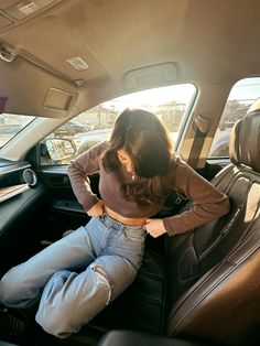 a woman sitting in the back seat of a car with her hands on her hips