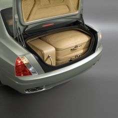 the back end of a silver car with its trunk open and luggage in it's compartment