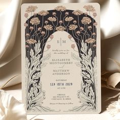 a wedding card with an arch and flowers on the front, surrounded by white satin