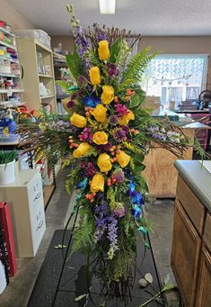 a cross made out of flowers and greenery in a room with other items on the floor