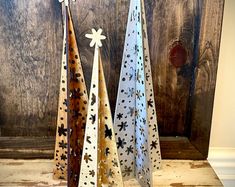 three metal christmas trees sitting on top of a wooden table