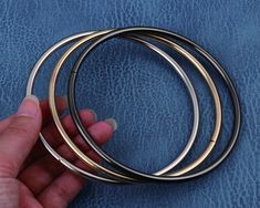 a hand is holding three metal rings on a blue leather surface, with one being held by the other