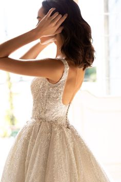 a woman in a wedding dress is touching her hair