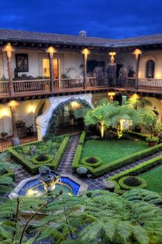 an outdoor courtyard with lots of greenery and lights on the walkway, surrounded by lush green plants