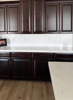 an empty kitchen with dark wood cabinets and white counter tops, is pictured in this image