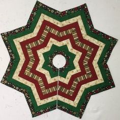 a green and red quilted star with a white center piece in the middle on a wall