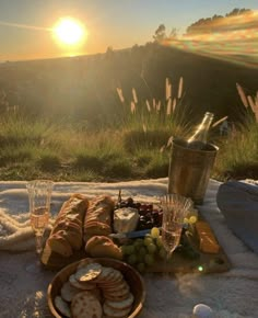 a picnic with bread, crackers and wine on a blanket in the sun setting