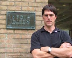 a man standing in front of a building with his arms crossed