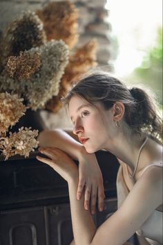 a young woman sitting next to a pile of dried flowers