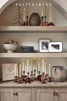 a shelf with candles and pictures on it