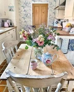 a wooden table topped with flowers in a kitchen