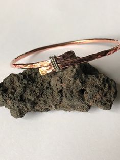 Rustic yet pretty copper bangle with a sterling silver detail The bangle is made of 2.6 mm copper wire, the ends was flatten and tied with sterling silver wire, then soldered (bangle is not adjustable).  This bangle will look good on its own, in combination with other bangles and can be worn by women and men, which is made it as a perfect gift for 7th wedding Anniversary for her or for him. It can be made in different sizes, so what if both of you would have matching bangles? Please choose size by the internal diameter.  The bangle is not covered with any lacquer, so it has all the copper's benefits.  For more versatile bangle please check out my shop www.leofwinejewellery.etsy.com Elegant Hand Wrapped Copper Bangle, Handmade Copper Bangle Bracelets, Hand Forged Copper Bangle Bracelet, Hammered Copper Bangle Bracelets, Hammered Copper Bangle Bracelet, Hand Wrapped Silver Copper Bangle, Adjustable Hammered Rose Gold Bangle, Hammered Rose Gold Bangle, Rose Gold Copper Bangle As Gift