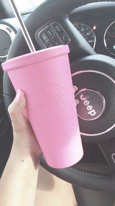 a pink starbucks cup sitting on top of a steering wheel