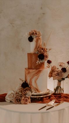 a three tiered cake sitting on top of a table next to two vases filled with flowers