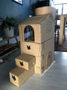 cardboard boxes stacked on top of each other in the shape of a house with a clock built into it