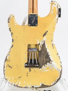 an old yellow electric guitar with some black knobs on it's back end