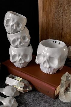 three white skulls sitting on top of a book next to crystal shards and other items