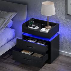 a night stand with two drawers and a lamp next to it on the side of a bed