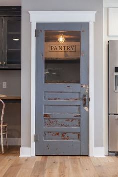 an old door is open to reveal the pantry in this modern kitchen with wood floors and stainless steel appliances