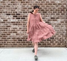 a woman in a dress is walking by a brick wall