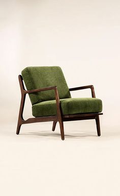 a green chair sitting on top of a white floor next to a wooden framed wall