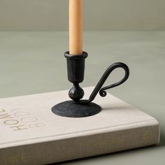 a candle is sitting on top of a book with an iron hook attached to it