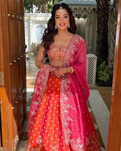 a woman in an orange and pink lehenga