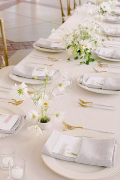 the table is set with white plates and napkins, silverware, and flowers