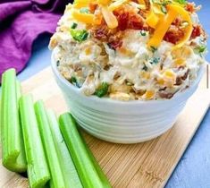 a white bowl filled with food next to celery on top of a wooden cutting board