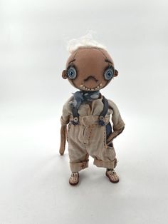 a doll with white hair and blue eyes is standing on a white background wearing overalls