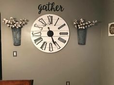 a clock mounted to the side of a wall next to two vases with flowers