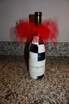 a wine bottle with a red bow on it sitting on a counter top next to a wall