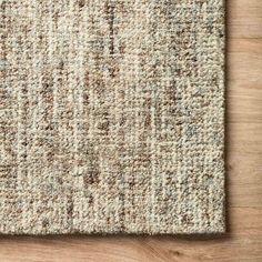 an area rug on top of a wooden floor with a white and brown color scheme